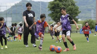 天然芝の上でボールを追いかける子どもたち